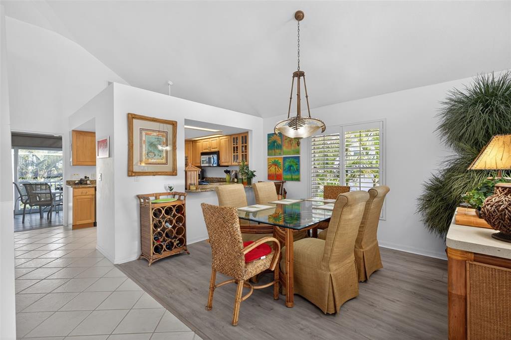 A dining area with a glass table, wicker chairs, and a view into the kitchen — 12130 SIESTA DRIVE, FORT MYERS BEACH, FL