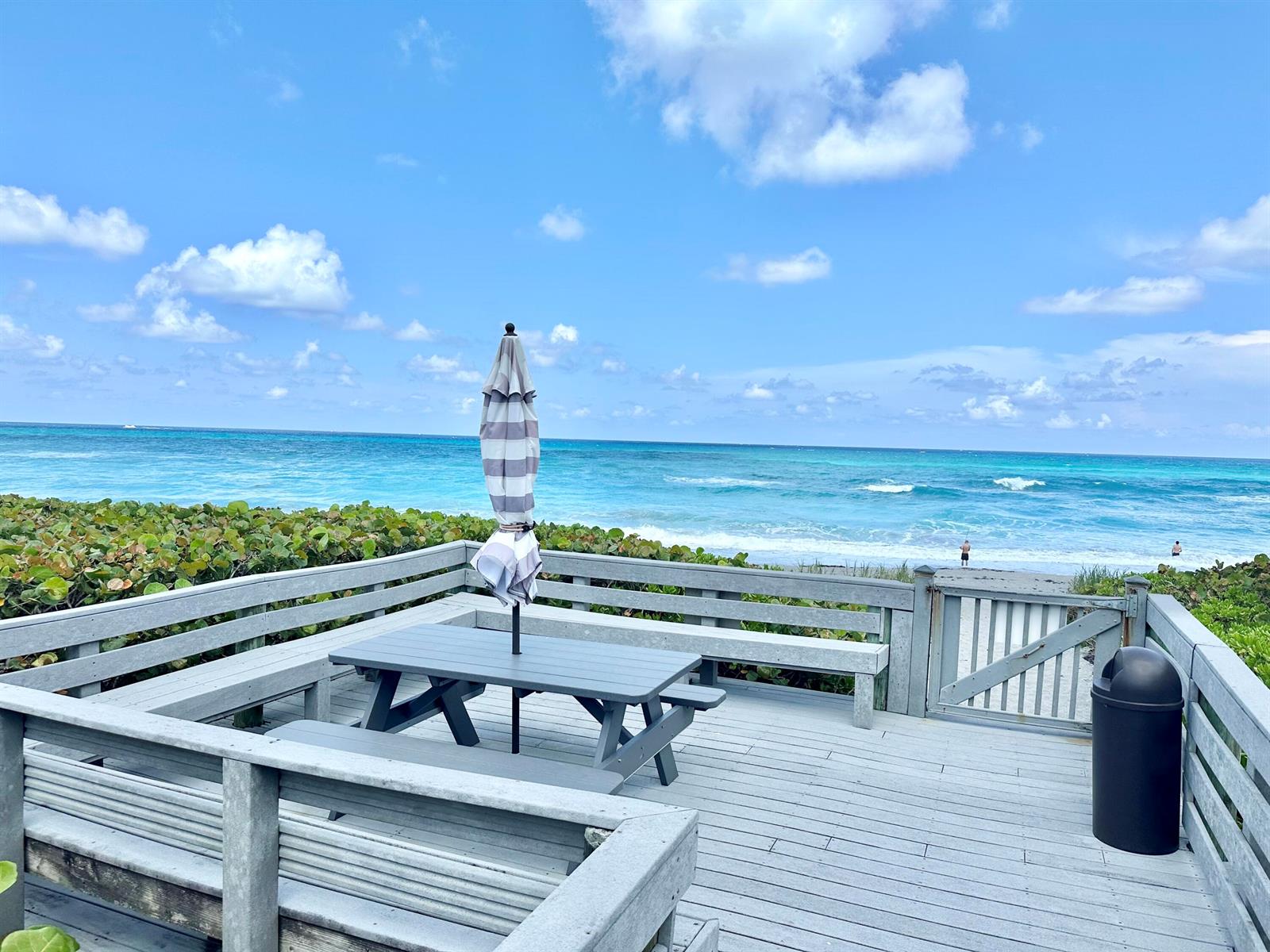 A wooden deck features a picnic table with an umbrella overlooking the ocean — 420 Celestial Way # 202, Juno Beach FL 33408, JUNO BEACH, FL