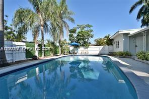 A swimming pool sits in a backyard with palm trees and a white fence — 250 SE Park St # 3, Dania Beach FL 33004, DANIA BEACH, FL