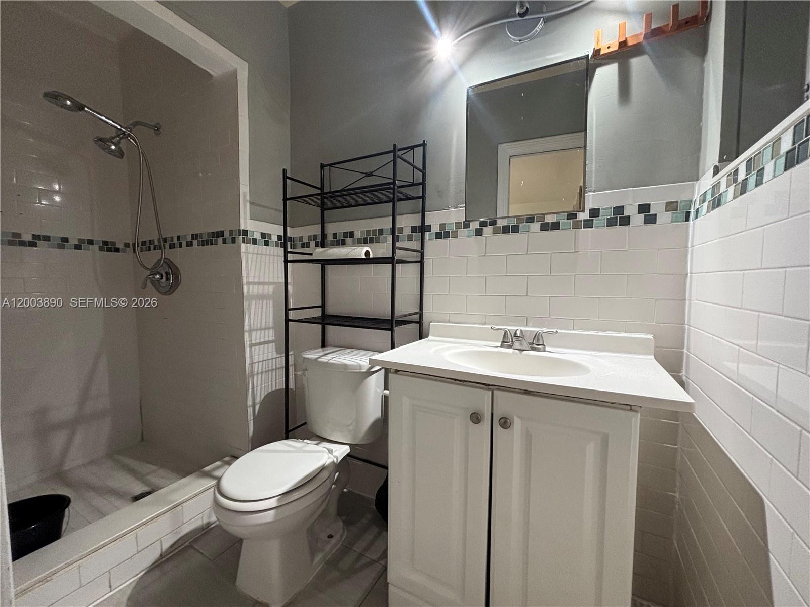 A bathroom features a white vanity, a toilet with a metal rack, and a tiled shower — 250 SE Park St # 3, Dania Beach FL 33004, DANIA BEACH, FL