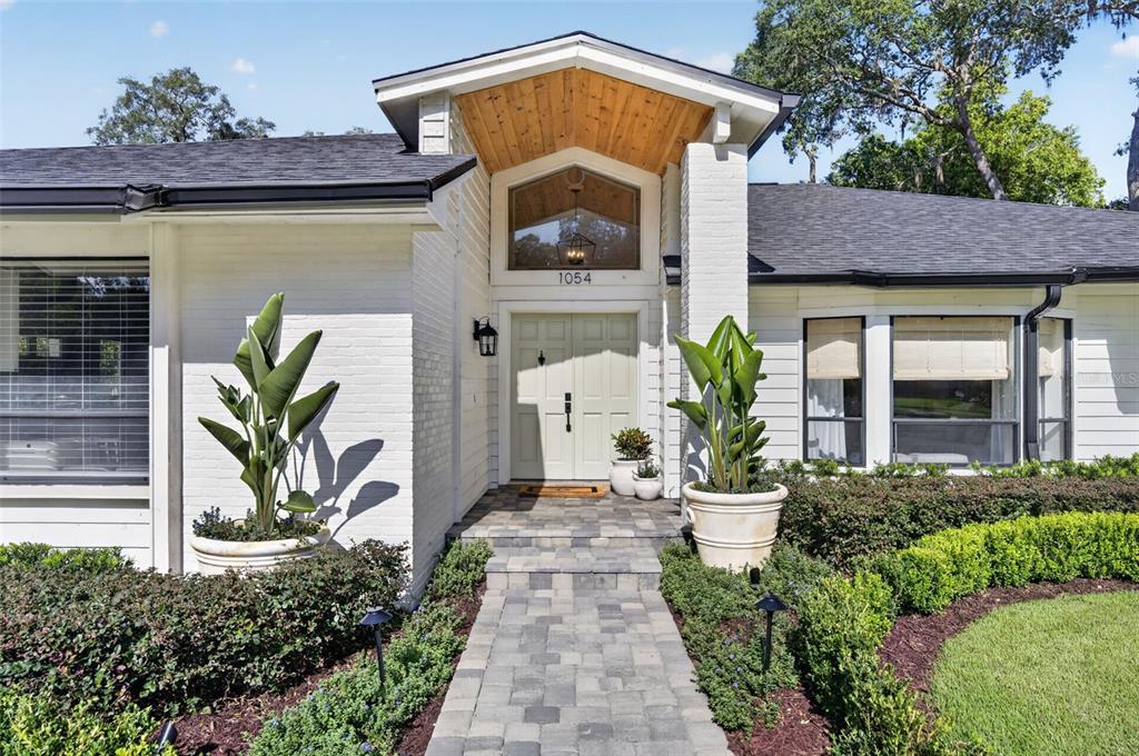 An aerial view shows a house with two screened-in pools and a paved driveway — 1054 WHISPERING COVE, CASSELBERRY, FL