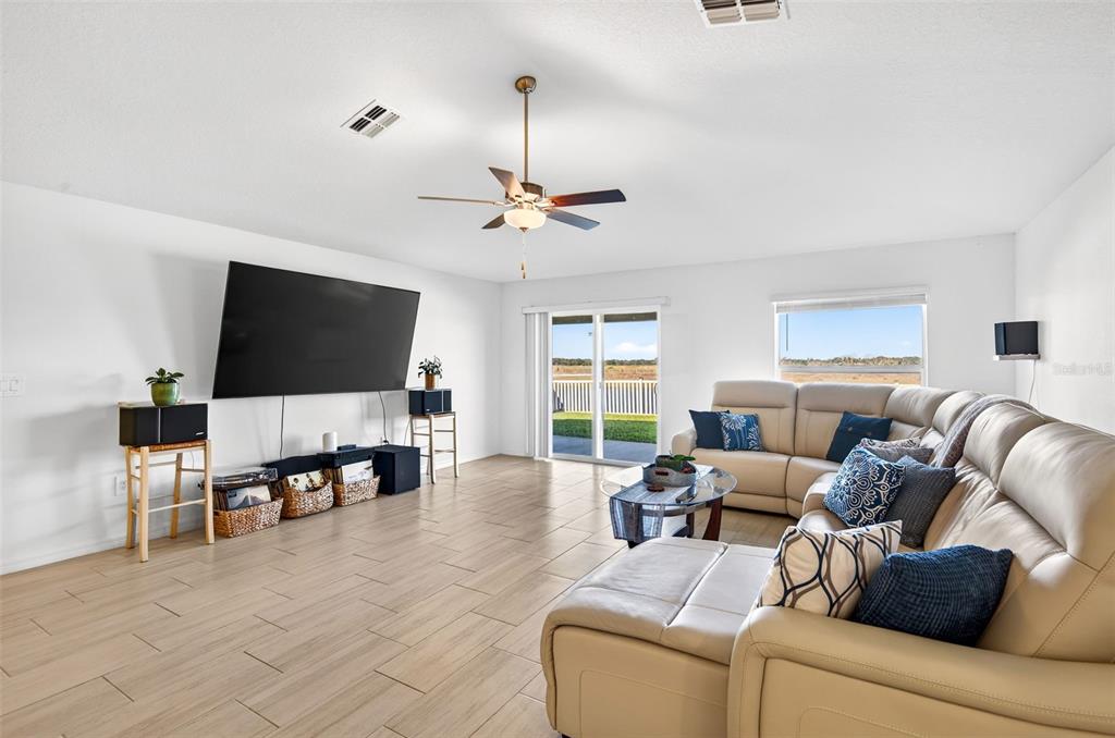 A living room features a large sectional sofa, a wall-mounted television, and tile flooring — 15217 ZIRCON RED DRIVE, WIMAUMA, FL