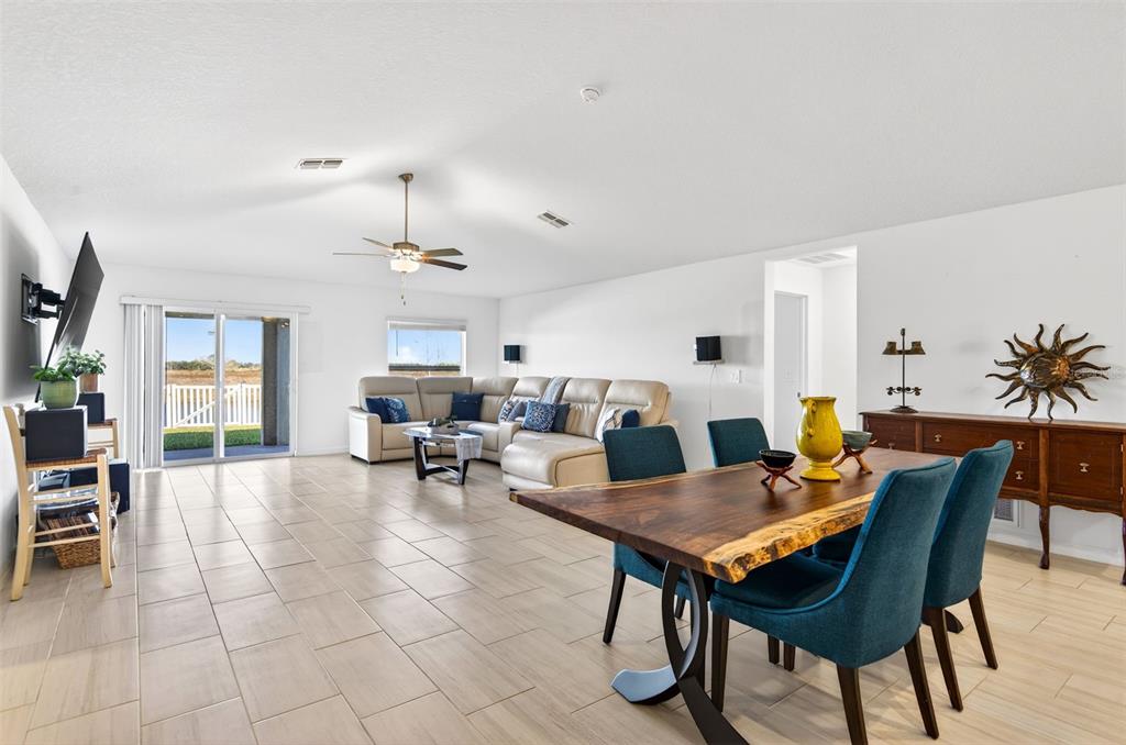 An open-concept living and dining area features tile flooring, a sectional sofa, and wood furniture — 15217 ZIRCON RED DRIVE, WIMAUMA, FL