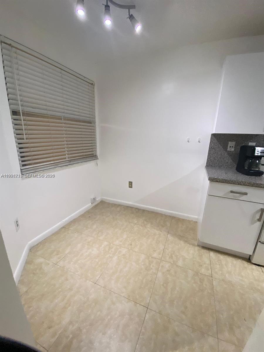 This kitchen area features light-colored tile flooring, white walls, and a window with blinds — 9761 NW 46th Ter # 107, Doral FL 33178, DORAL, FL