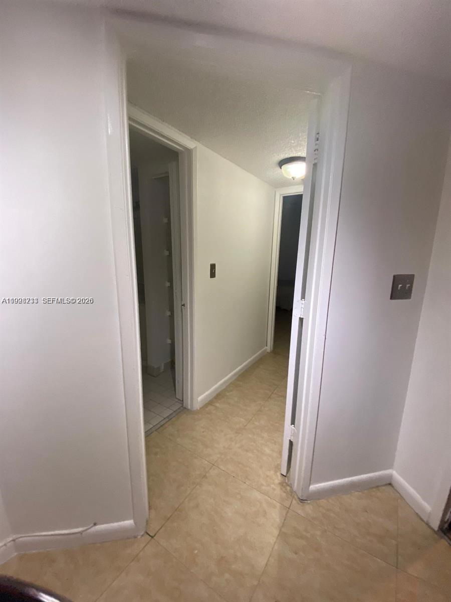 A hallway with light-colored tile flooring leads to two doorways — 9761 NW 46th Ter # 107, Doral FL 33178, DORAL, FL