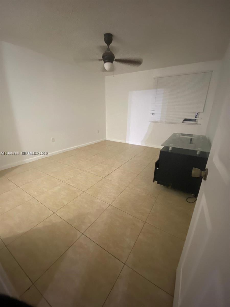 An empty room features white walls, a ceiling fan, and light-colored square floor tiles — 9761 NW 46th Ter # 107, Doral FL 33178, DORAL, FL