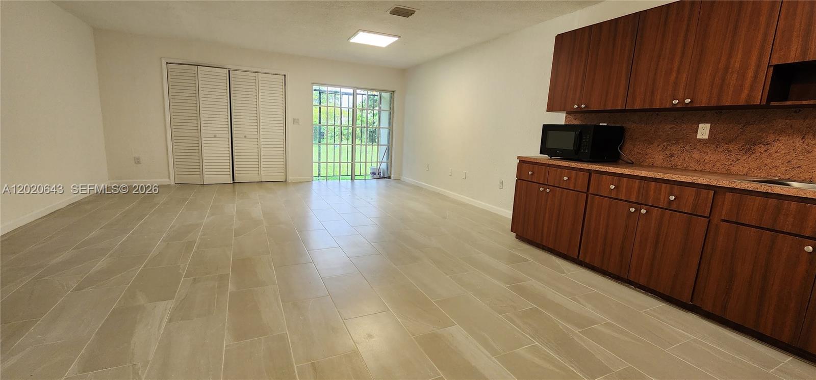 This room features light-colored tile flooring, white walls, wooden cabinets, and a sliding glass door — 10380 NW 10th Ave # 10380, Miami FL 33150, MIAMI, FL