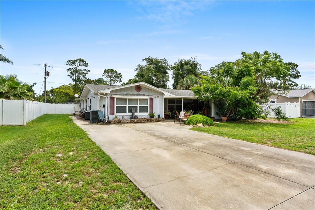 A single-story house with a concrete driveway, a front porch, and a white vinyl fence — 1945 FERN PALM DRIVE, EDGEWATER, FL