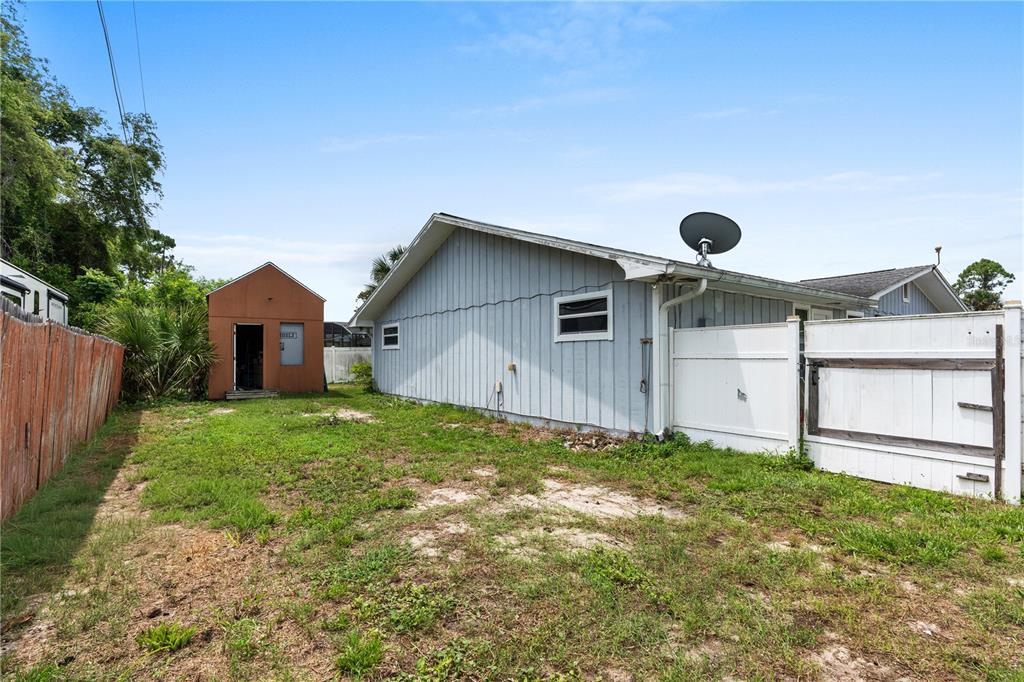 The exterior of a house with light blue siding, a shed, and a white fence — 1945 FERN PALM DRIVE, EDGEWATER, FL