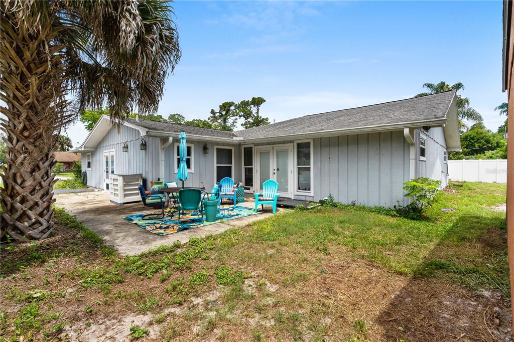 A backyard view of a single-story house with light blue siding, a patio, and palm tree — 1945 FERN PALM DRIVE, EDGEWATER, FL