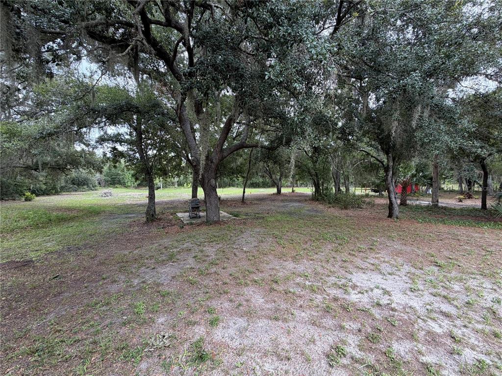 An aerial view shows a single-story house with a brown roof, red porch, and gravel driveway — 14150 HIGHLAND ROAD, WIMAUMA, FL