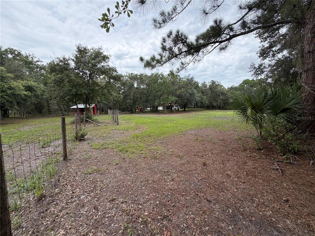 An aerial view shows a house nestled in a wooded lot near a dirt road — 14150 HIGHLAND ROAD, WIMAUMA, FL