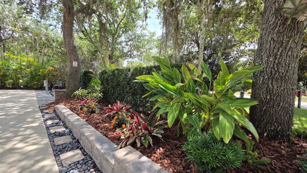A landscaped garden bed with a stone retaining wall sits beside a concrete driveway — 233 STALLION LANE, RIVER RANCH, FL