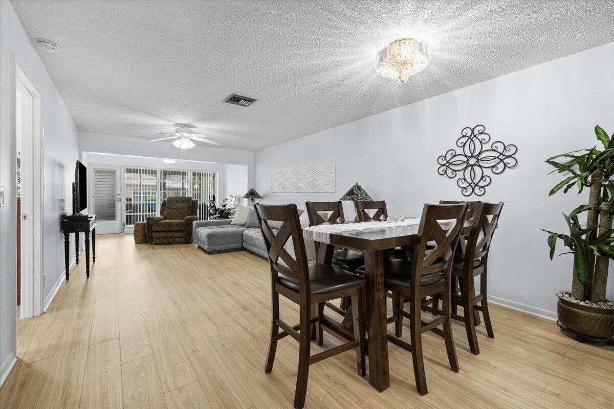A dining area with a wooden table and chairs opens into a living room space — 1031 Citrus Way # a, Delray Beach FL 33445, DELRAY BEACH, FL