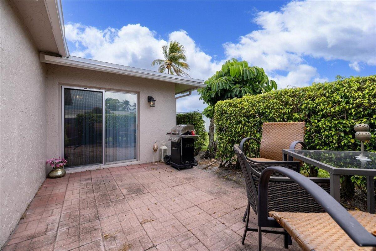 A paved patio features a grill, outdoor dining furniture, and a sliding glass door — 1031 Citrus Way # a, Delray Beach FL 33445, DELRAY BEACH, FL