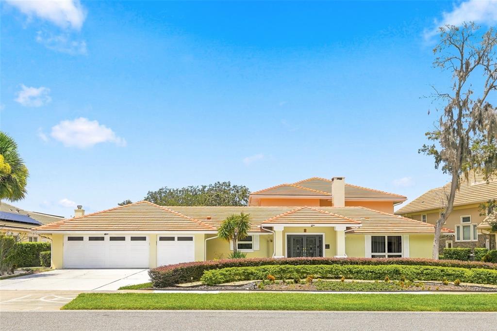 A single-story house with a tile roof, three-car garage, and a landscaped front yard — 5912 TARAWOOD DRIVE, ORLANDO, FL