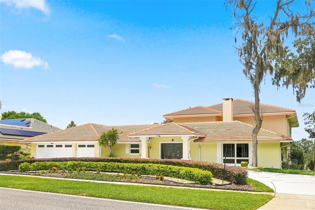A two-story house with a tile roof, light-colored stucco, and a manicured hedge in front — 5912 TARAWOOD DRIVE, ORLANDO, FL