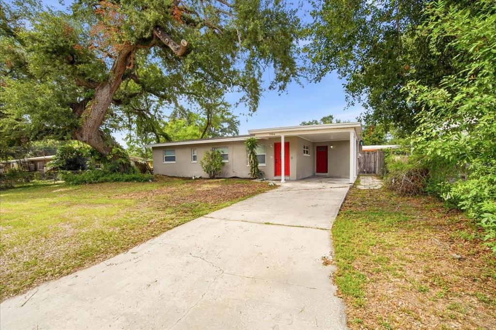 A single-story house with a concrete driveway, a carport, and two red front doors — 7506 CORAL VINE LANE, TAMPA, FL