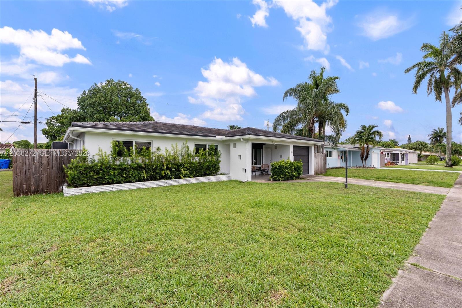 A white single-story house features a front lawn, a hedge, and a paved driveway — 706 N 32nd Ct, Hollywood FL 33021, HOLLYWOOD, FL