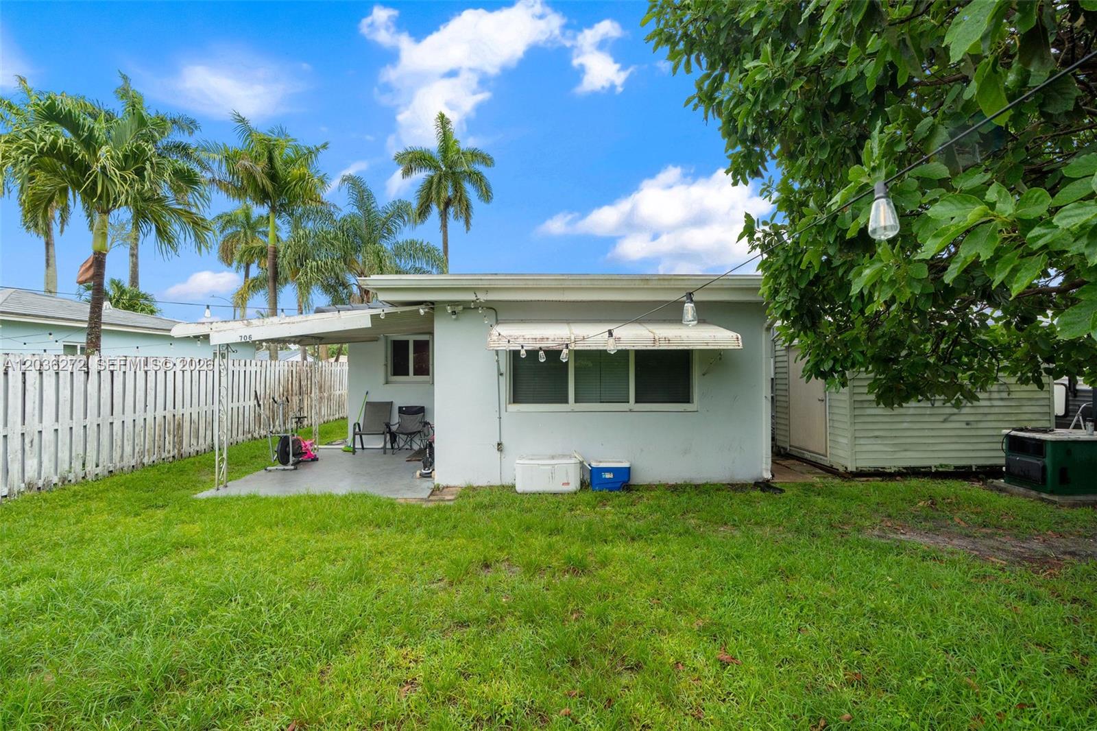 The exterior of a small, light-colored house features a covered patio and a grassy yard — 706 N 32nd Ct, Hollywood FL 33021, HOLLYWOOD, FL
