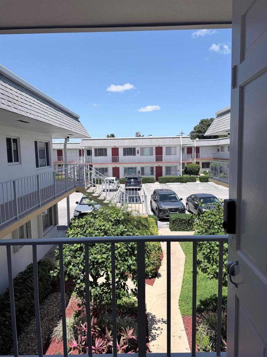 A view from a balcony overlooking a courtyard with parking and apartment buildings — 3322 Cynthia Lane # 207, FL 33461, FL