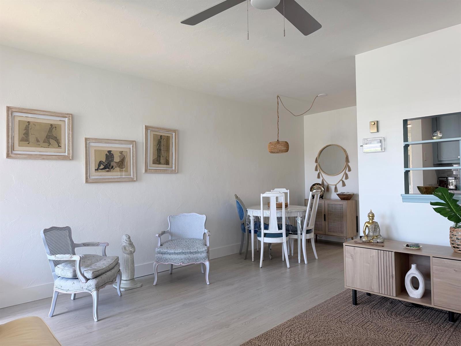 A bright living and dining area features light wood flooring, vintage-style chairs, and framed artwork — 3322 Cynthia Lane # 207, FL 33461, FL