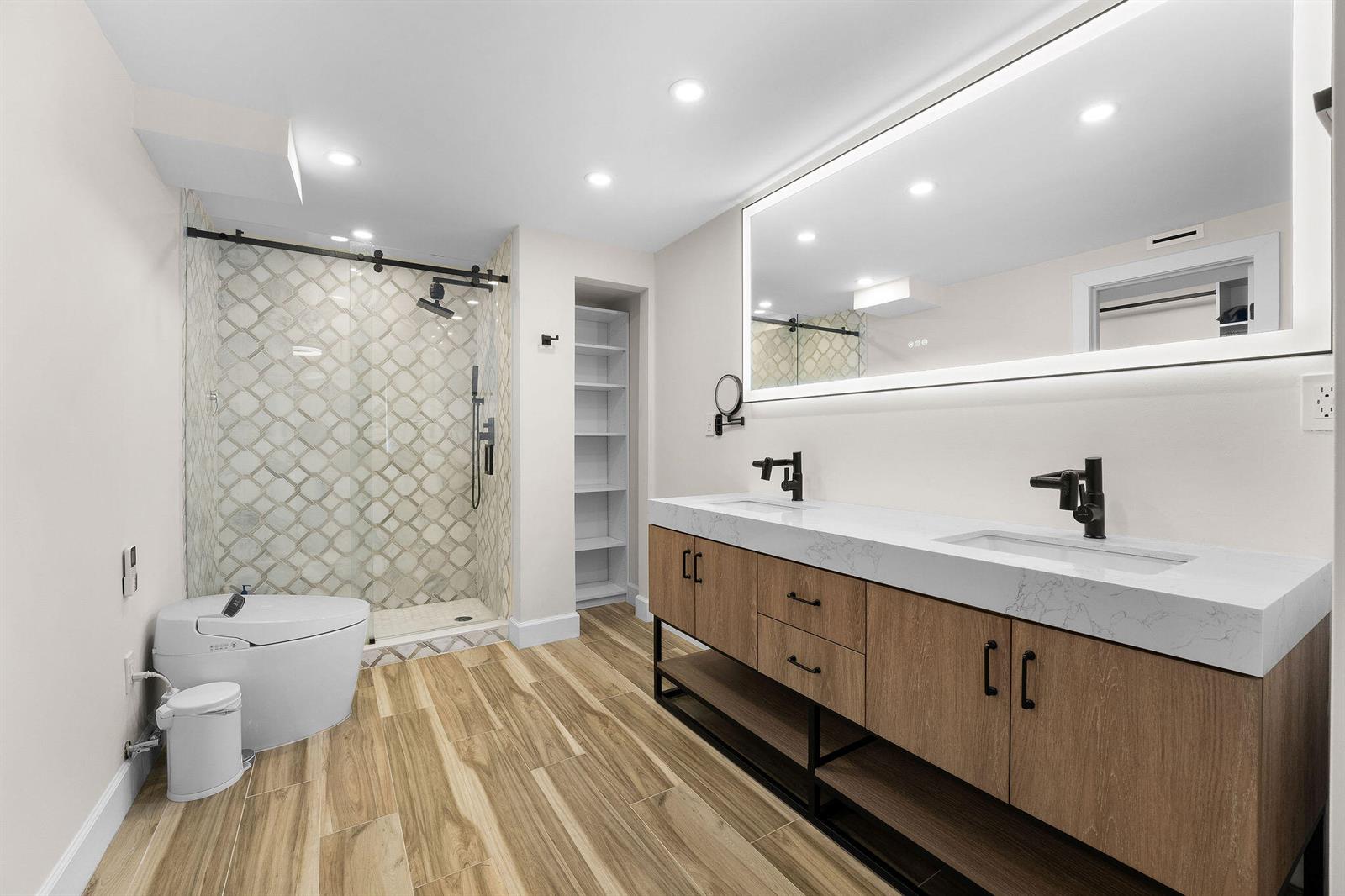 A modern bathroom features a double vanity, a glass-enclosed shower, and wood-look tile flooring — 911 Ocean Drive # 201, Juno Beach FL 33408, JUNO BEACH, FL