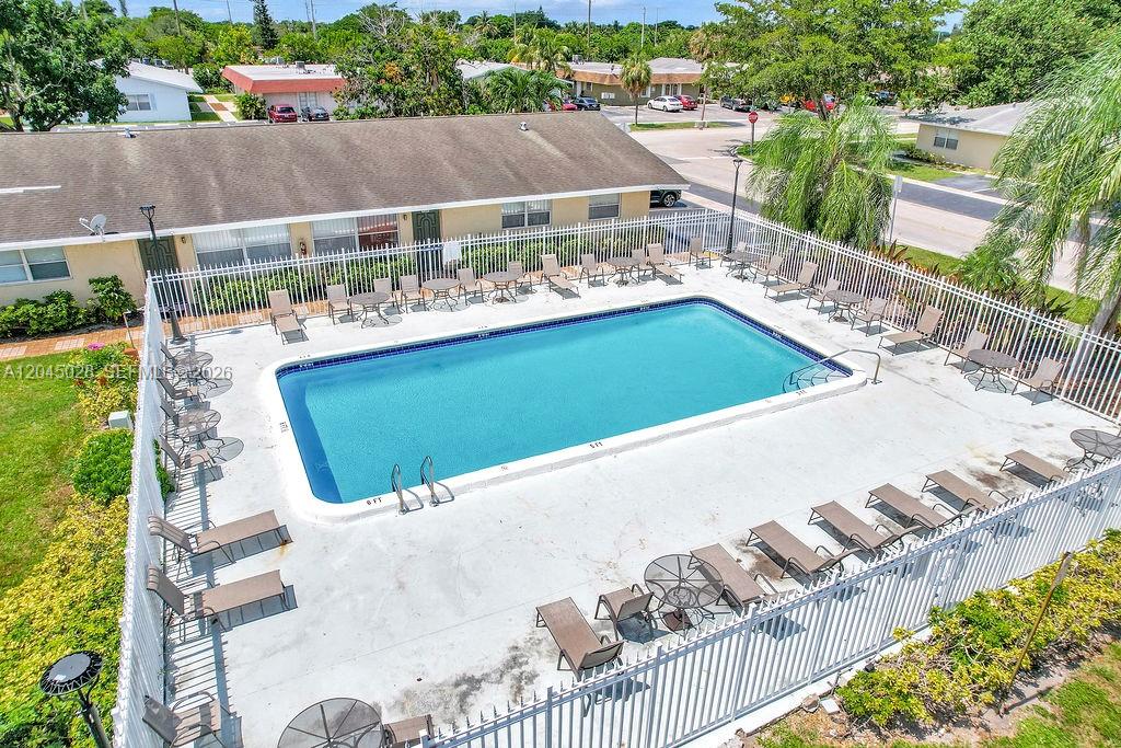 An aerial view shows a rectangular swimming pool surrounded by lounge chairs and patio tables — 6890 SW 5th St, Margate FL 33068, MARGATE, FL