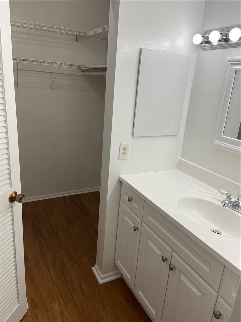 A bathroom vanity with white cabinets and a walk-in closet with wire shelving — 3253 Foxcroft Road # G212, Miramar FL 33025, MIRAMAR, FL