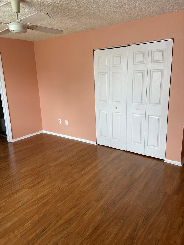 A bedroom with peach walls, wood-look flooring, and white bi-fold closet doors — 3253 Foxcroft Road # G212, Miramar FL 33025, MIRAMAR, FL
