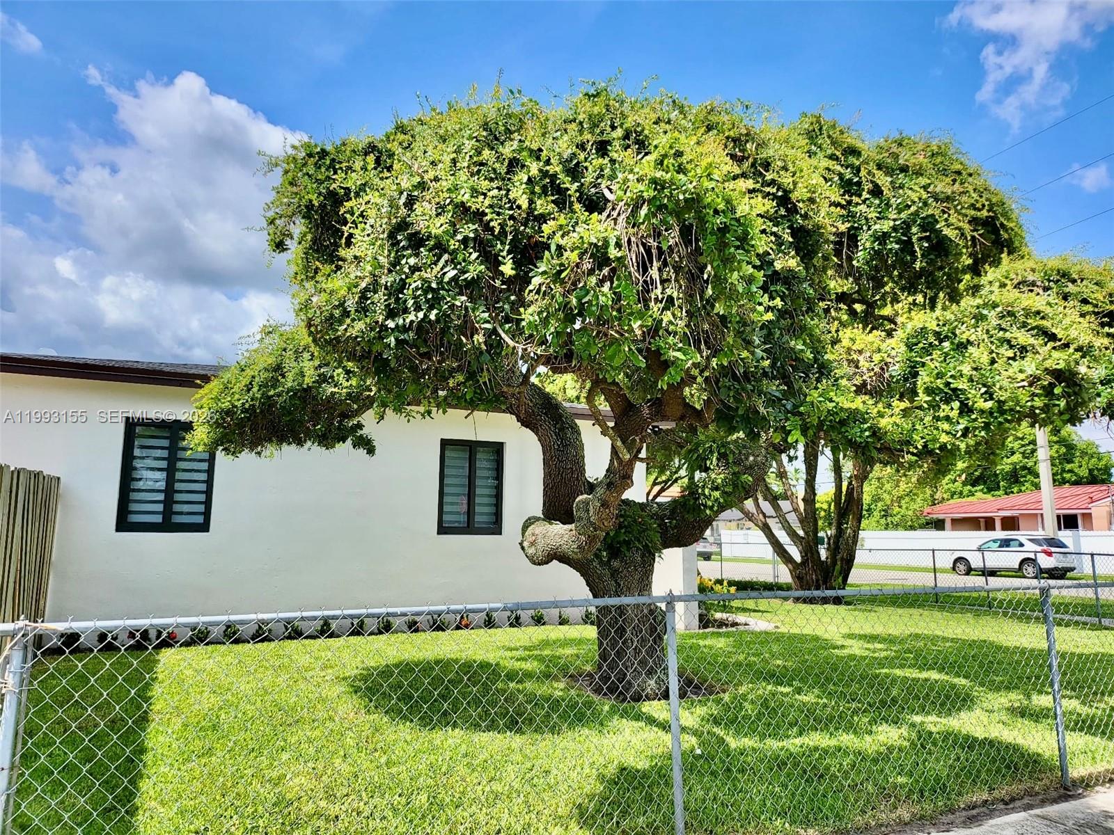A single-story house with a white exterior, dark window frames, and a chain-link fence — 201 SW 62nd Ave, Miami FL 33144, MIAMI, FL