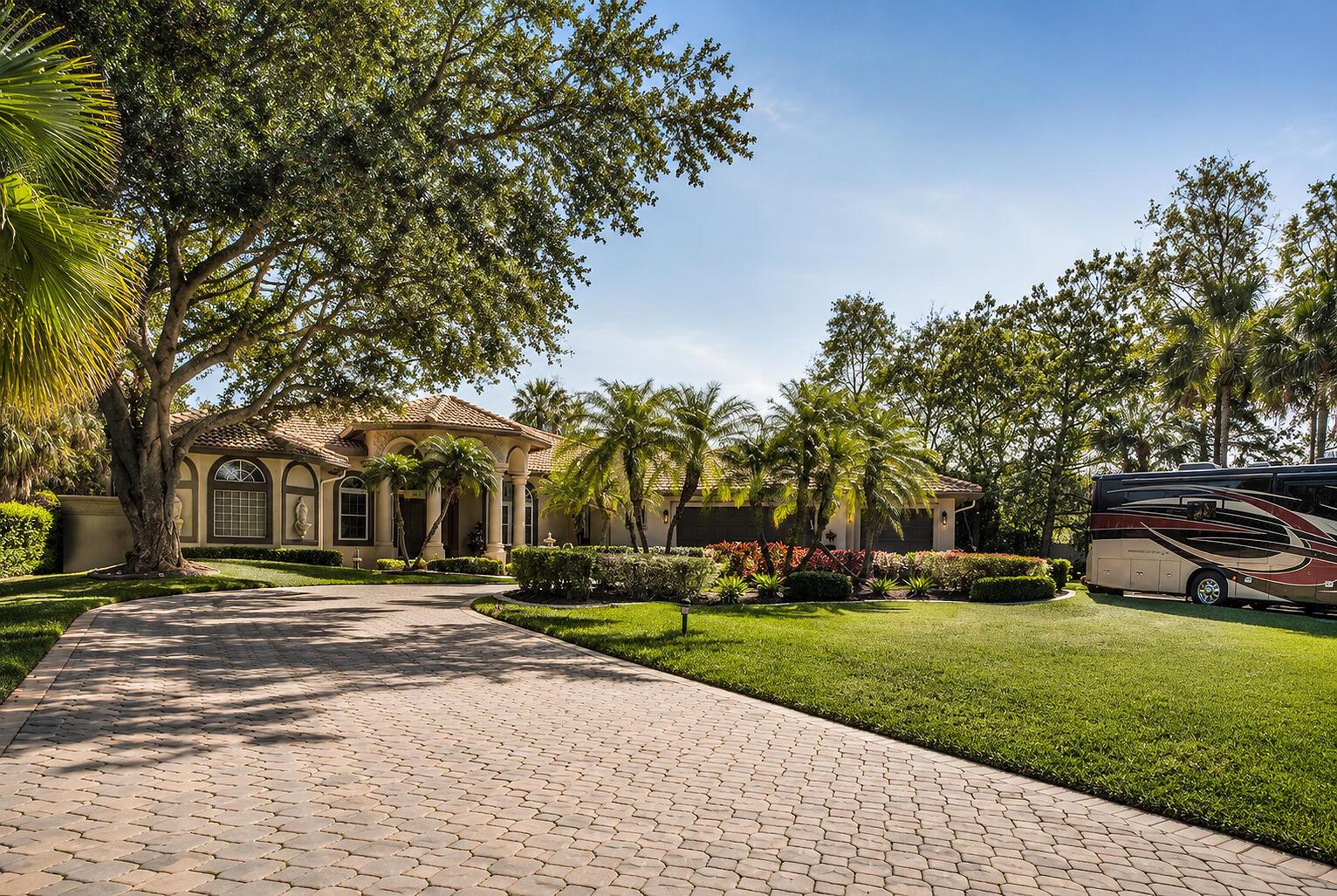 A paved driveway leads to a single-story house with a large tree and parked RV — 5884 NW 79th Way, Parkland FL 33067, PARKLAND, FL