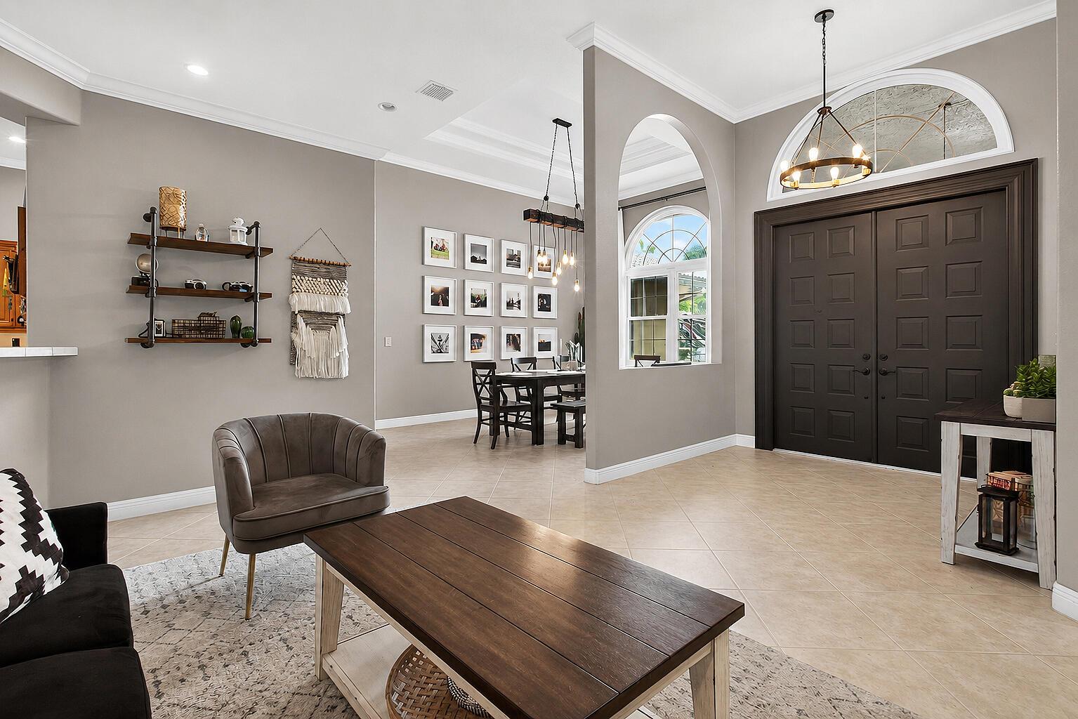 A living room with a dark wood coffee table, gray armchair, and an adjacent dining area — 5884 NW 79th Way, Parkland FL 33067, PARKLAND, FL