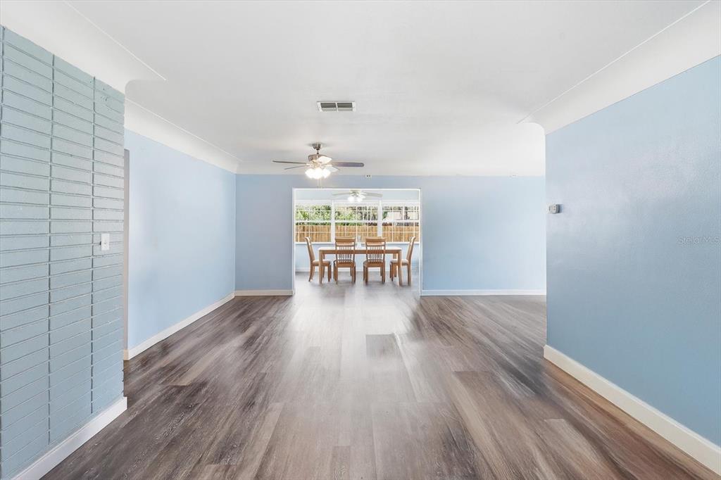 A living room with light blue walls and wood-look flooring leads to a dining area — 9451 W GREEN BAY LANE, CRYSTAL RIVER, FL