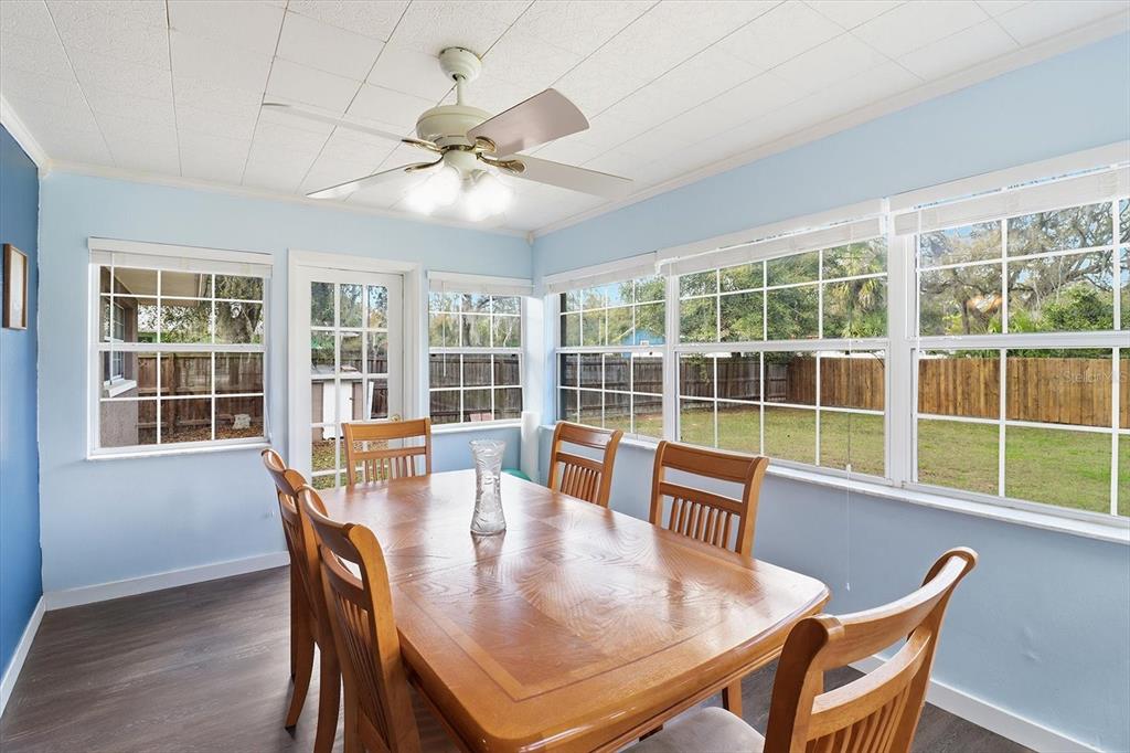 A dining room with light blue walls, a wooden table, and large windows overlooking a yard — 9451 W GREEN BAY LANE, CRYSTAL RIVER, FL