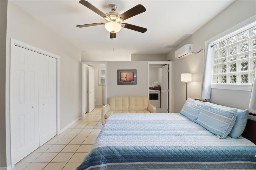 A bedroom features a ceiling fan, tiled floors, a bed, a sofa, and glass blocks — 9451 W GREEN BAY LANE, CRYSTAL RIVER, FL