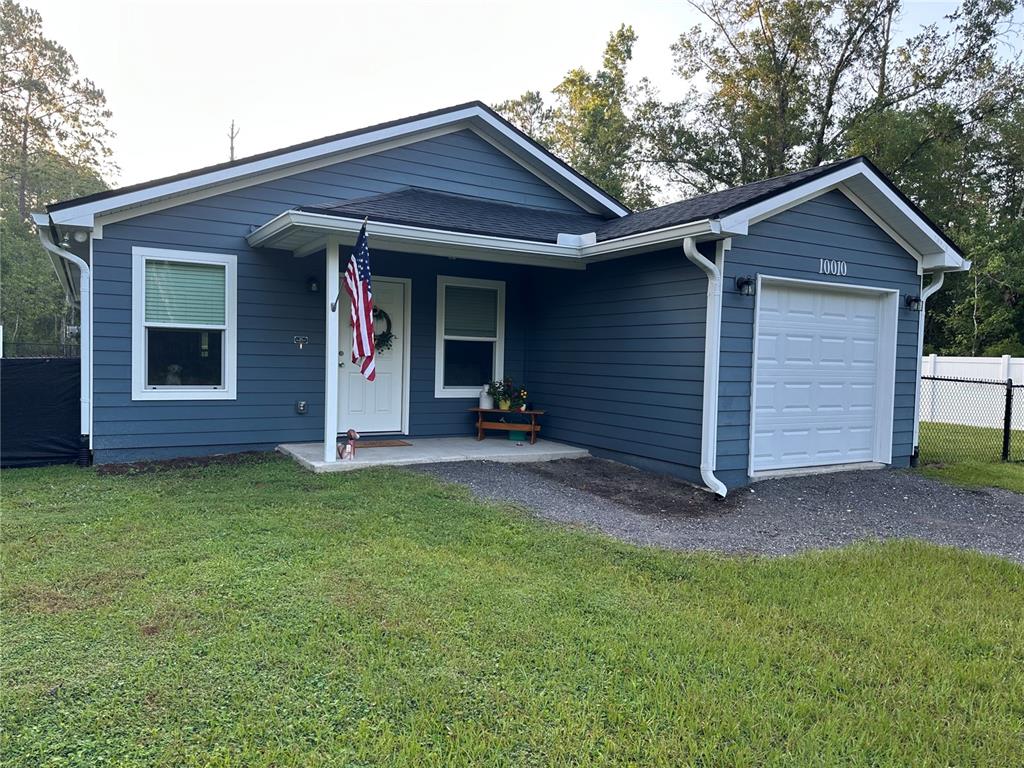 A blue single-story house with a white garage door, front porch, and gravel driveway — 10010 MCMAHON AVENUE, HASTINGS, FL
