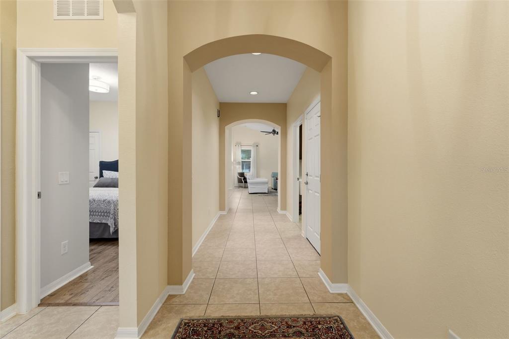 A bedroom features wood-look flooring, a red bedspread, a white nightstand, and a window — 8956 39TH STREET CIRCLE E, PARRISH, FL