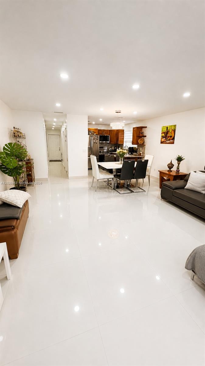 A bright, open-concept living and dining area features white tile floors and a modern kitchen — 401 SW 109th Ave # 14, Miami FL 33174, MIAMI, FL