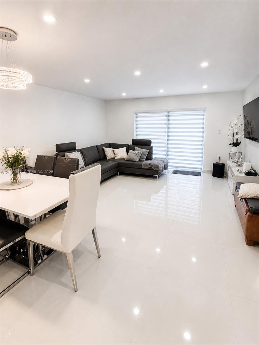 A modern living and dining area features white tile floors, a sectional sofa, and lighting — 401 SW 109th Ave # 14, Miami FL 33174, MIAMI, FL
