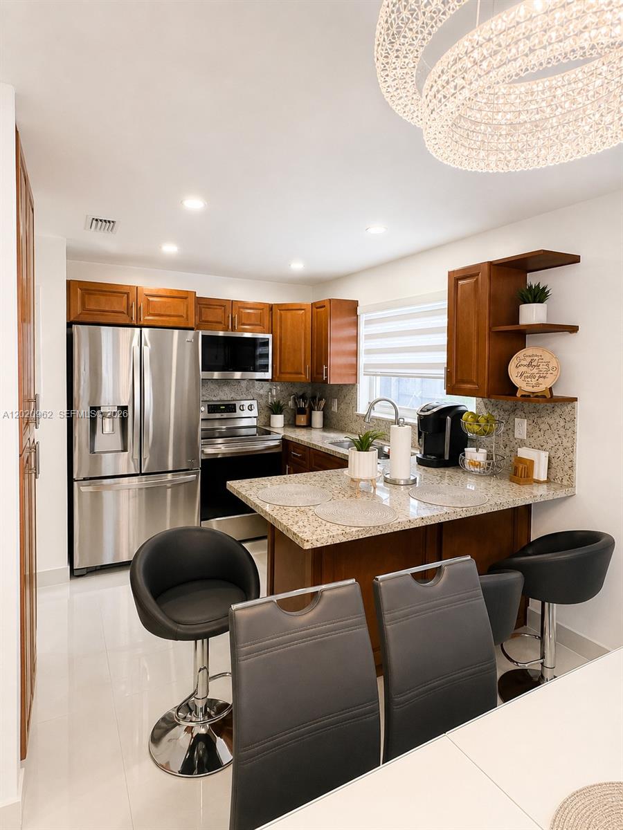 A kitchen features wood cabinets, stainless steel appliances, granite countertops, and a breakfast bar — 401 SW 109th Ave # 14, Miami FL 33174, MIAMI, FL