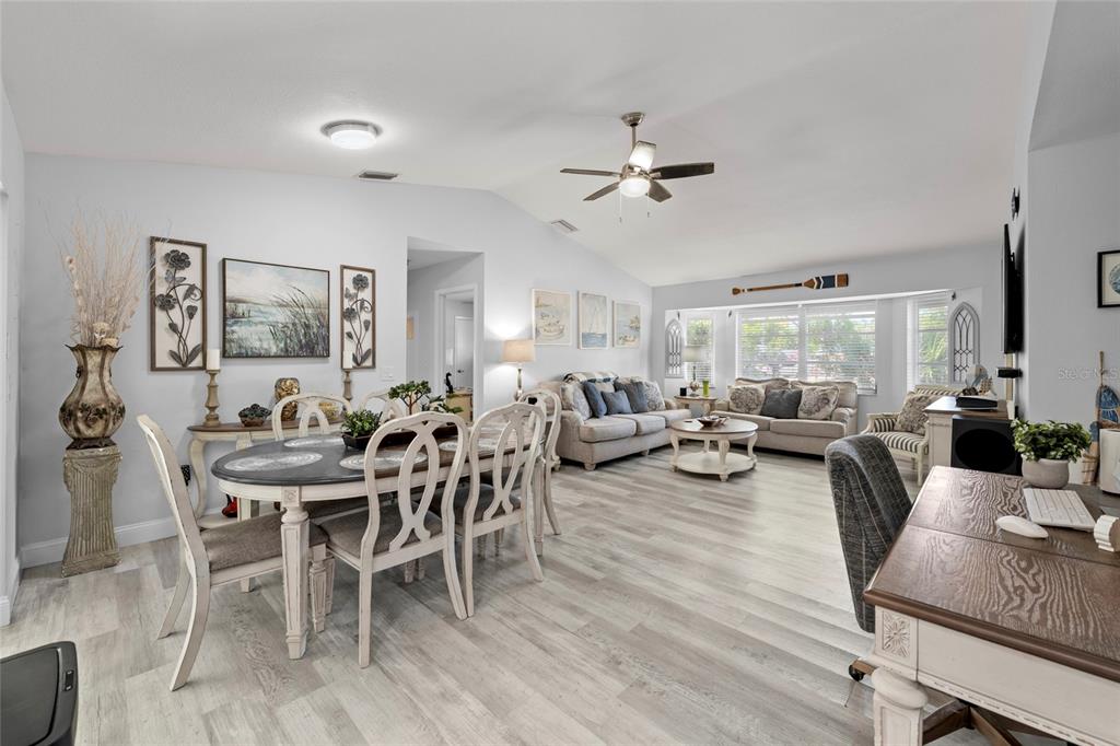 A bright, open-concept living and dining area features light wood-look flooring and vaulted ceilings — 935 BAER AVENUE NW, PORT CHARLOTTE, FL