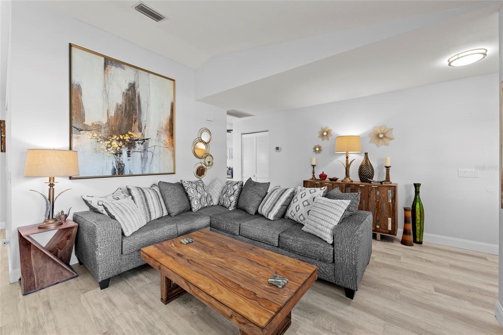 A living room features a gray sectional sofa, a wooden coffee table, and wall art — 935 BAER AVENUE NW, PORT CHARLOTTE, FL
