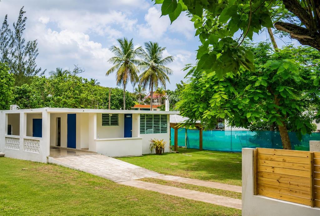 A white single-story house with a driveway, palm trees, and a wooden fence in front — PR 681 KM 11.7 ISLOTE WARD, ARECIBO, PR