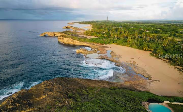 An aerial view of a sandy beach, rocky coastline, and ocean with a small pool nearby — PR 681 KM 11.7 ISLOTE WARD, ARECIBO, PR
