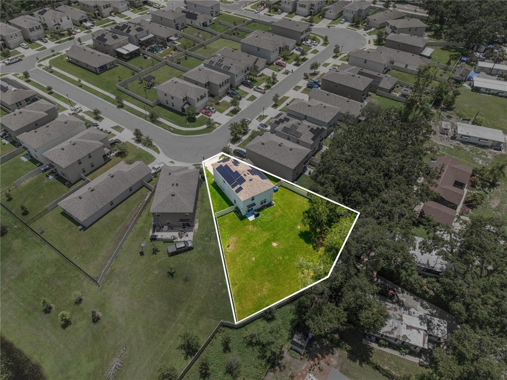 An aerial view shows a two-story house with solar panels and a large fenced backyard — 10823 TRAILING VINE DRIVE, TAMPA, FL