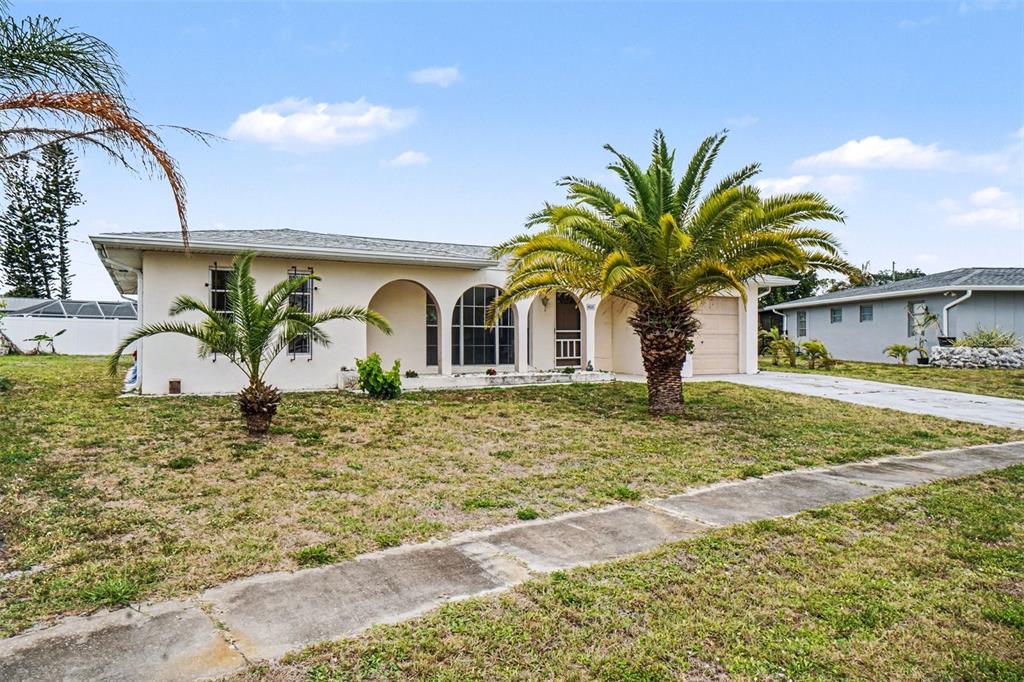 A single-story house with a beige stucco exterior, arched windows, and two palm trees — 6535 MARIUS ROAD, NORTH PORT, FL
