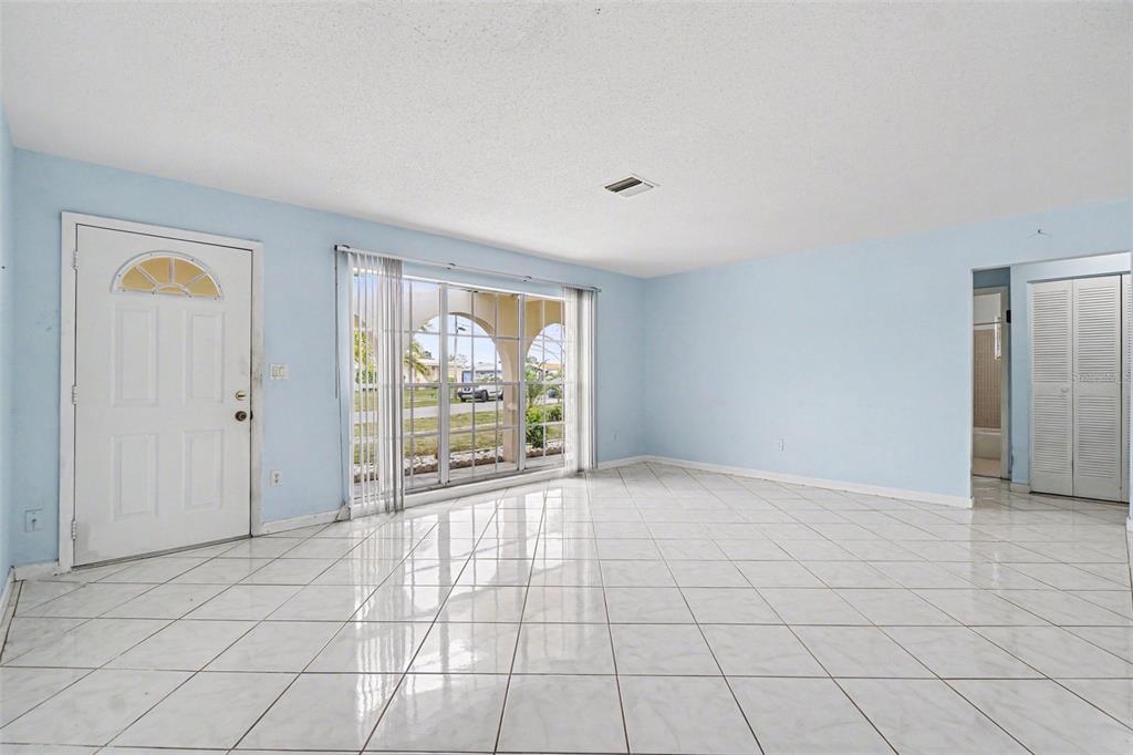 A bright room features light blue walls, white tiled floors, a front door, and large windows — 6535 MARIUS ROAD, NORTH PORT, FL