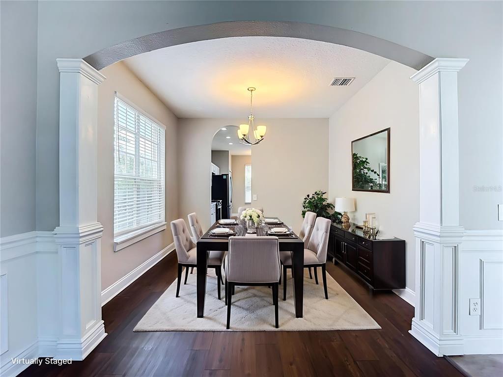 A dining room features a dark wood table, upholstered chairs, and an arched entryway — 10739 EVENINGWOOD COURT, TRINITY, FL
