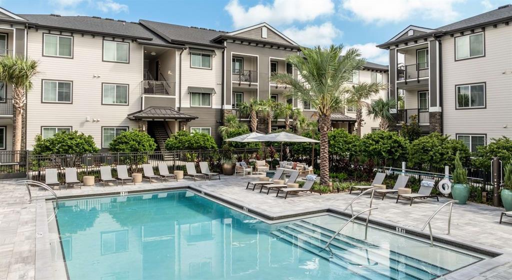 A swimming pool and hot tub are situated in the courtyard of a multi-story apartment complex — 5000 COLLINA TERRACE UNIT TH1, CLERMONT, FL
